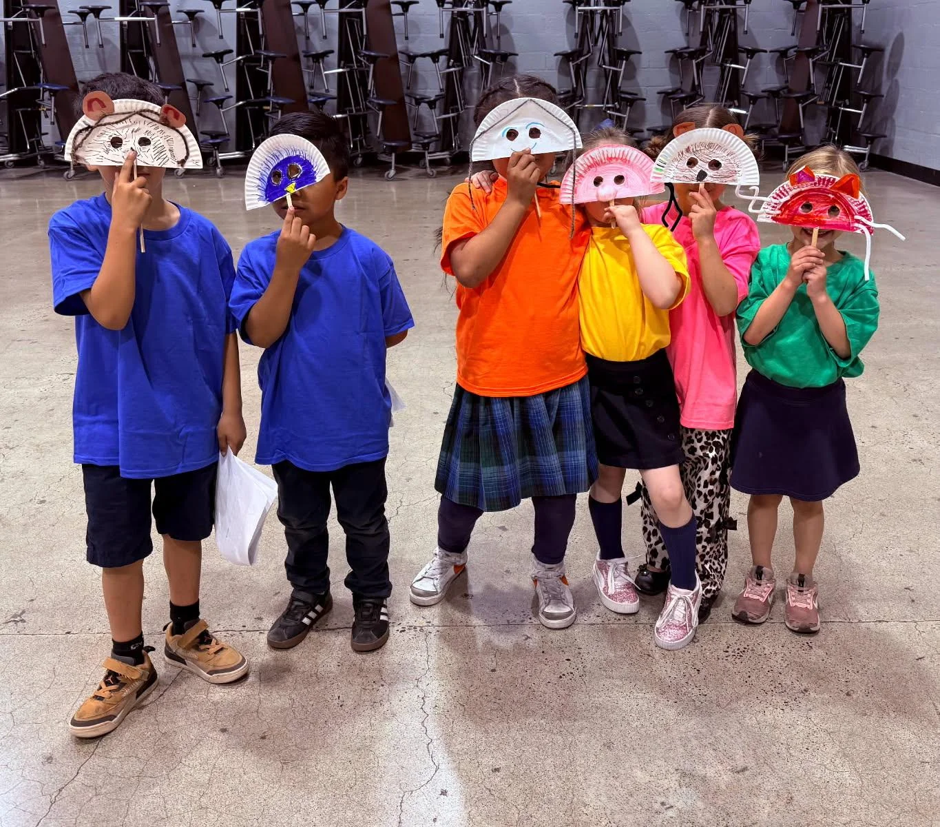 Children holding colorful handmade animal masks during a reading-group activity