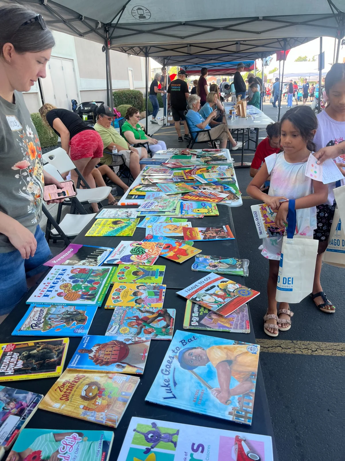 Children and adults choosing books at a community table